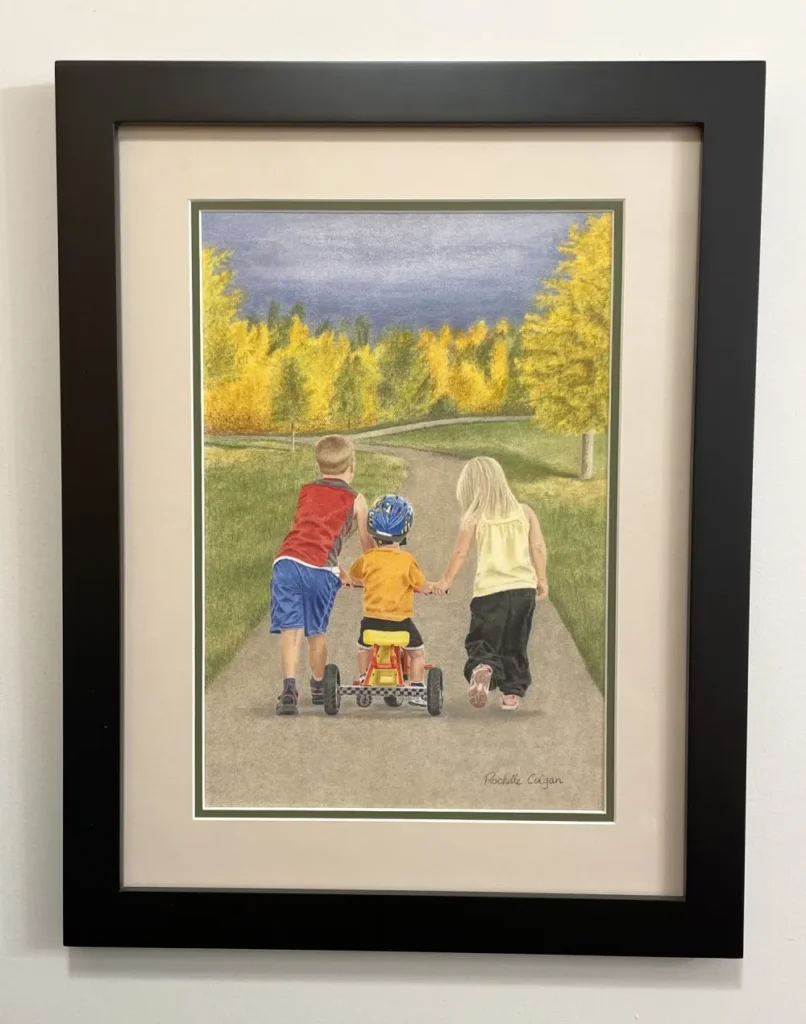 Framed and matted realistic drawing of an autumn scene with two children walking on a path, guiding a third child on a tricycle. By Alberta artist Rochelle Colgan