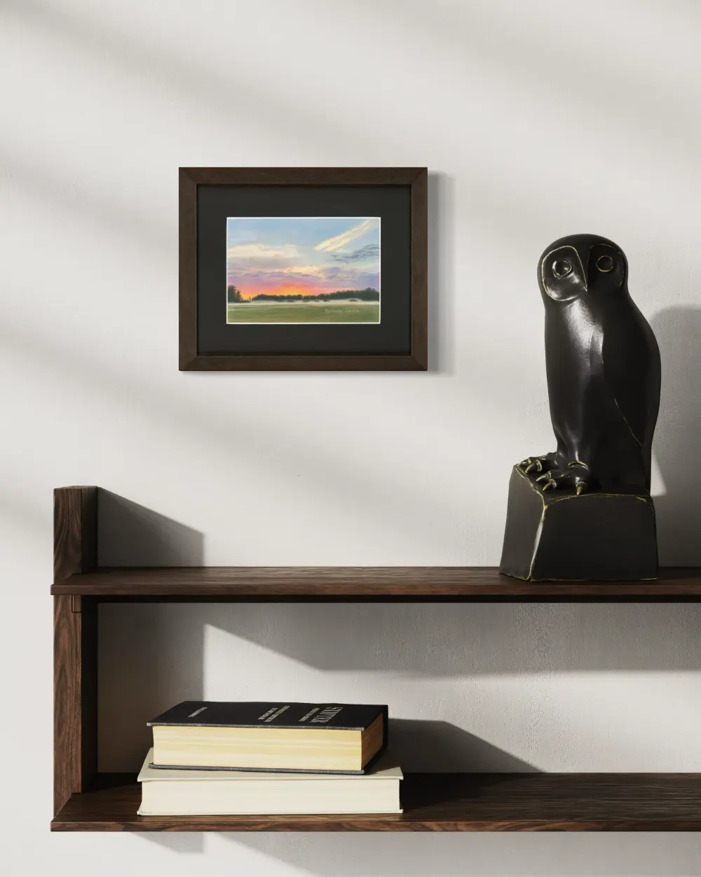 Framed colourful sunrise skyscape drawing with mist, trees and a green grass field, hanging on a wall. By Alberta artist Rochelle Colgan